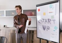 Młody founder prezentuje strategię startupu przy flipcharcie indoors
